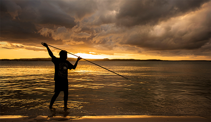 An Aboriginal man spearfishing at a beach.